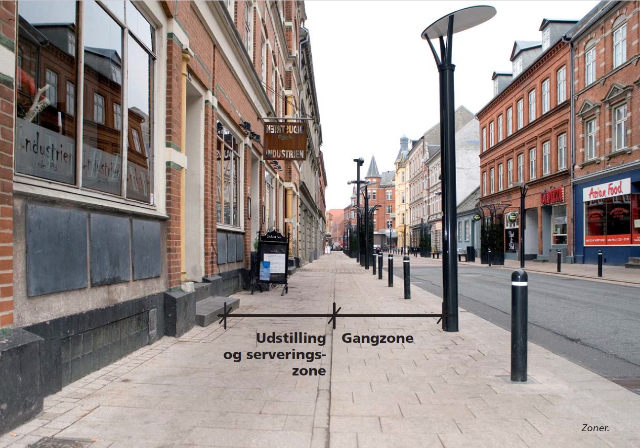 Foto der viser opdelingen af fortovsarealet i Skolegade i henholdsvis udstillings- og serveringszonen nærmest bygningerne samt gangzonen nærmest vejarealet. 